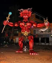 An almost 30 feet Narkasur effigy displayed in front of a 2-storeyed house along with a smaller effigy.